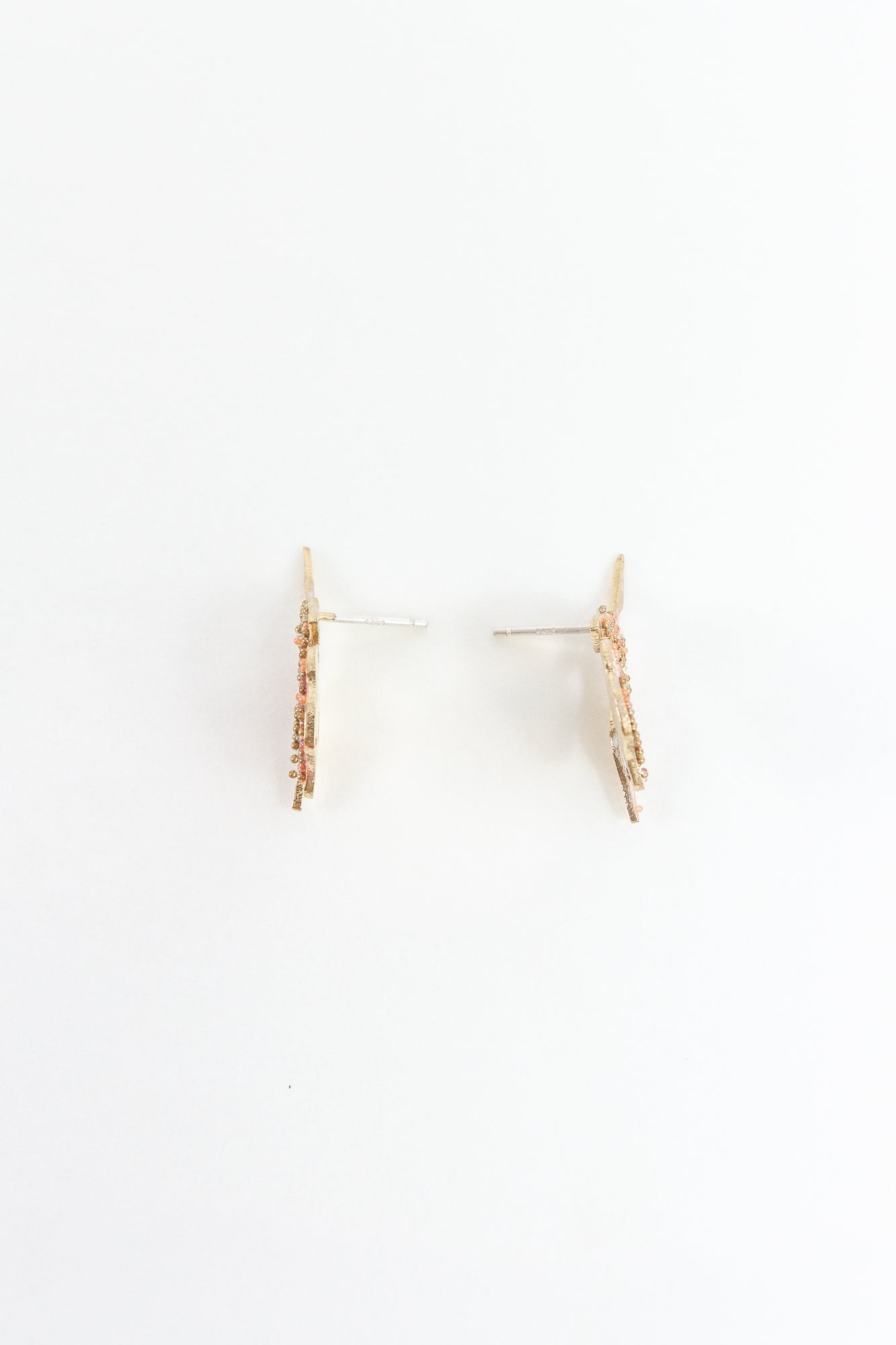 Side view of the red elderberry stud earrings showing the spike and volume of the gold-plated brass piece.