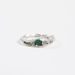 Top view of a silver ring with a textured band and an oval green gemstone.