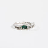 Top view of a silver ring with a textured band and an oval green gemstone.
