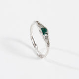 Silver ring with an organic band and a deep green gemstone, photographed on a white background