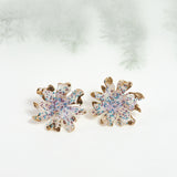 Wild clover stud earrings on a light background with blurred branches, highlighting their botanical design and handcrafted finish.