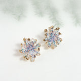 Wild clover stud earrings on a light background with blurred branches, highlighting their botanical design and handcrafted finish.