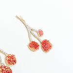 Close-up detail of the textured, hand-painted design of the Agraz Earrings in shades of red.