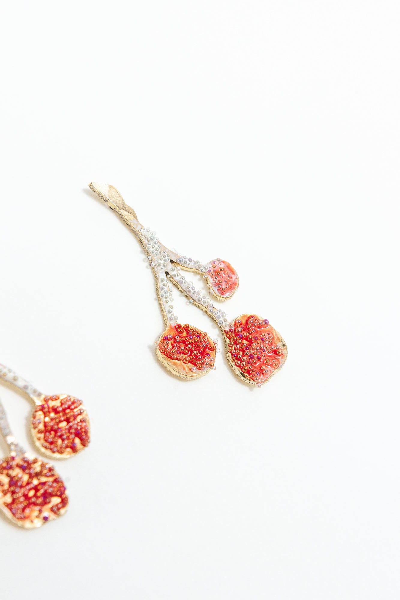 Close-up detail of the textured, hand-painted design of the Agraz Earrings in shades of red.