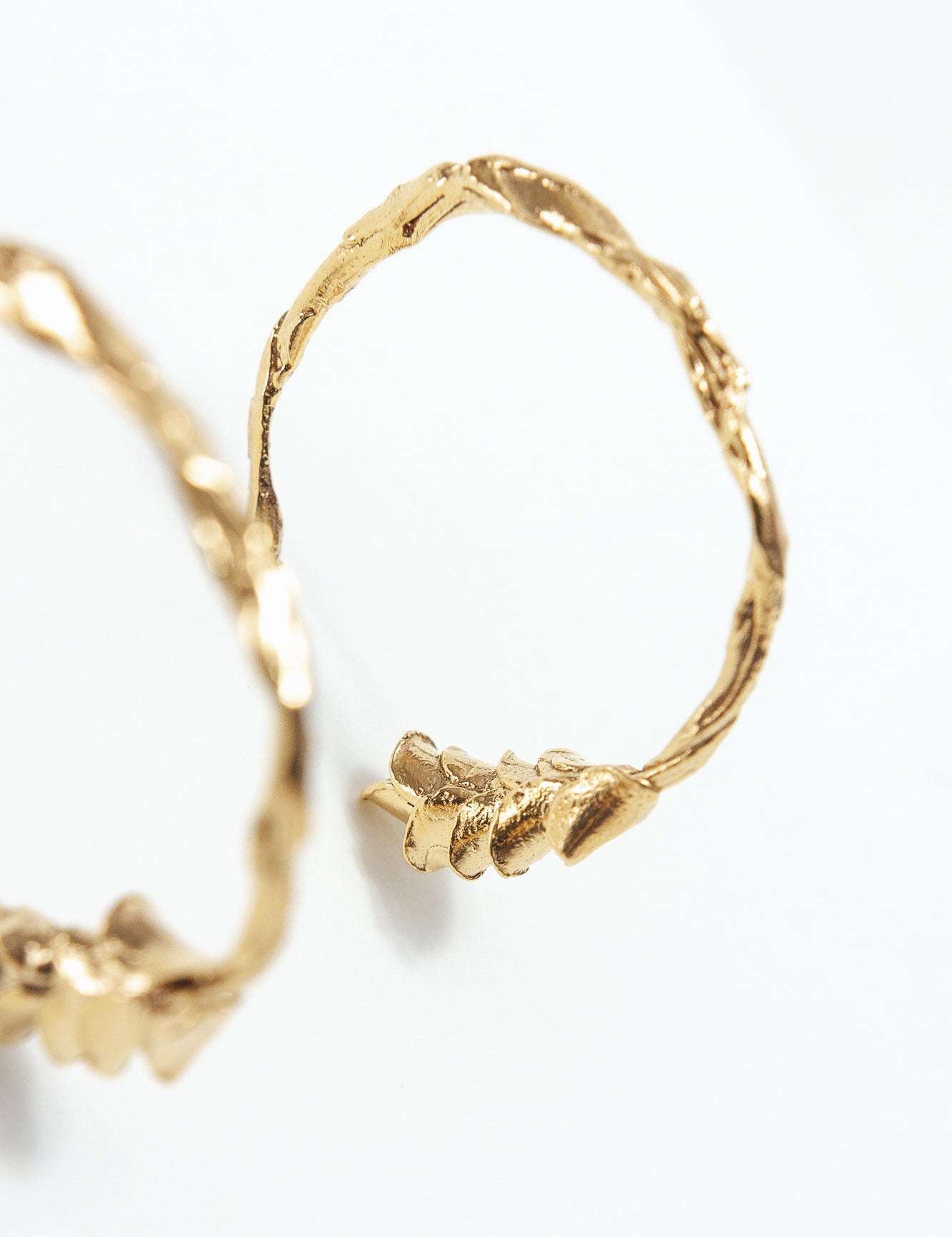 Macro detail of the gold Espiga hoop earrings, showing handcrafted texture and gold-plated finish.