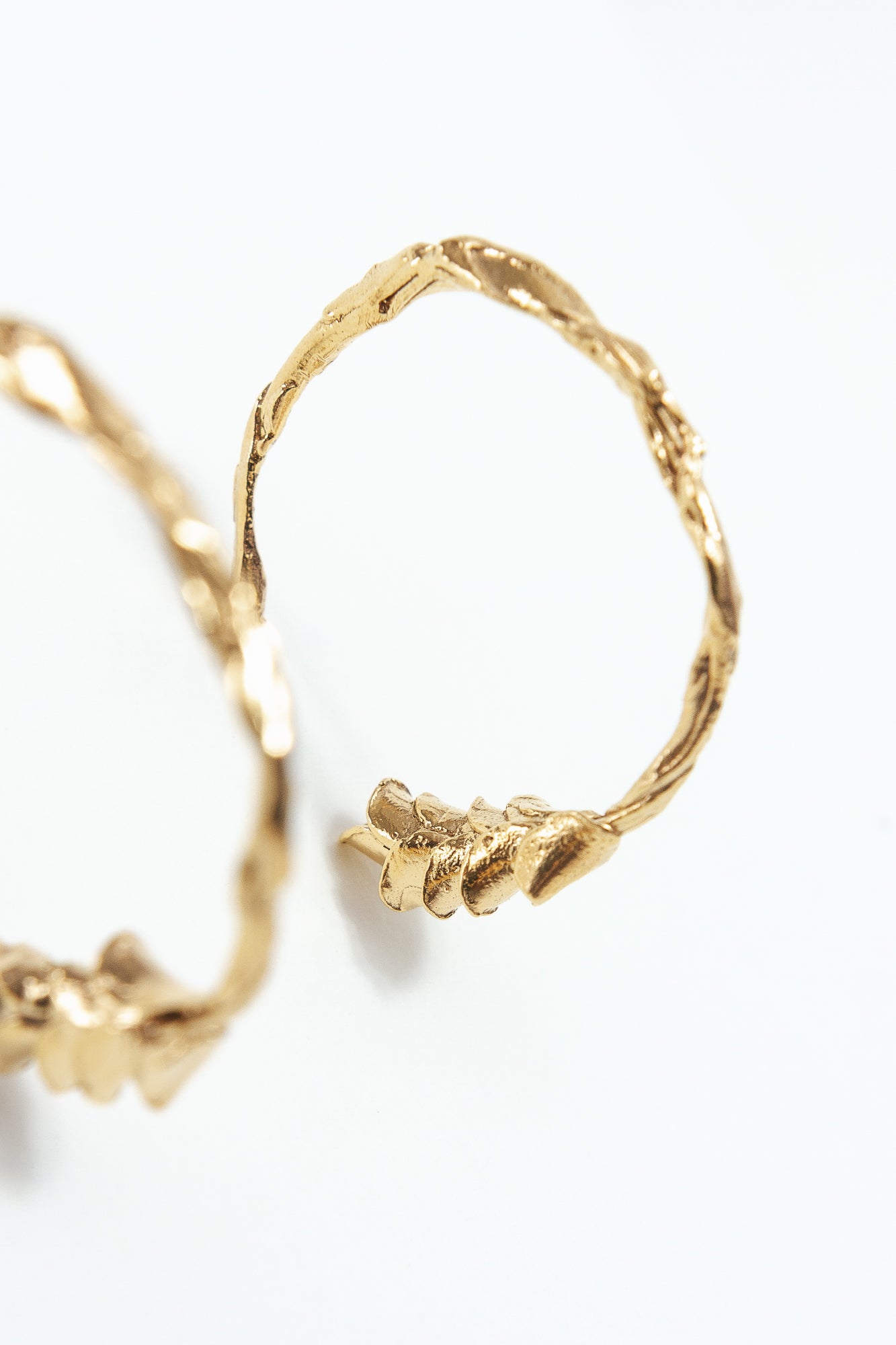 Macro detail of the gold Espiga hoop earrings, showing handcrafted texture and gold-plated finish.