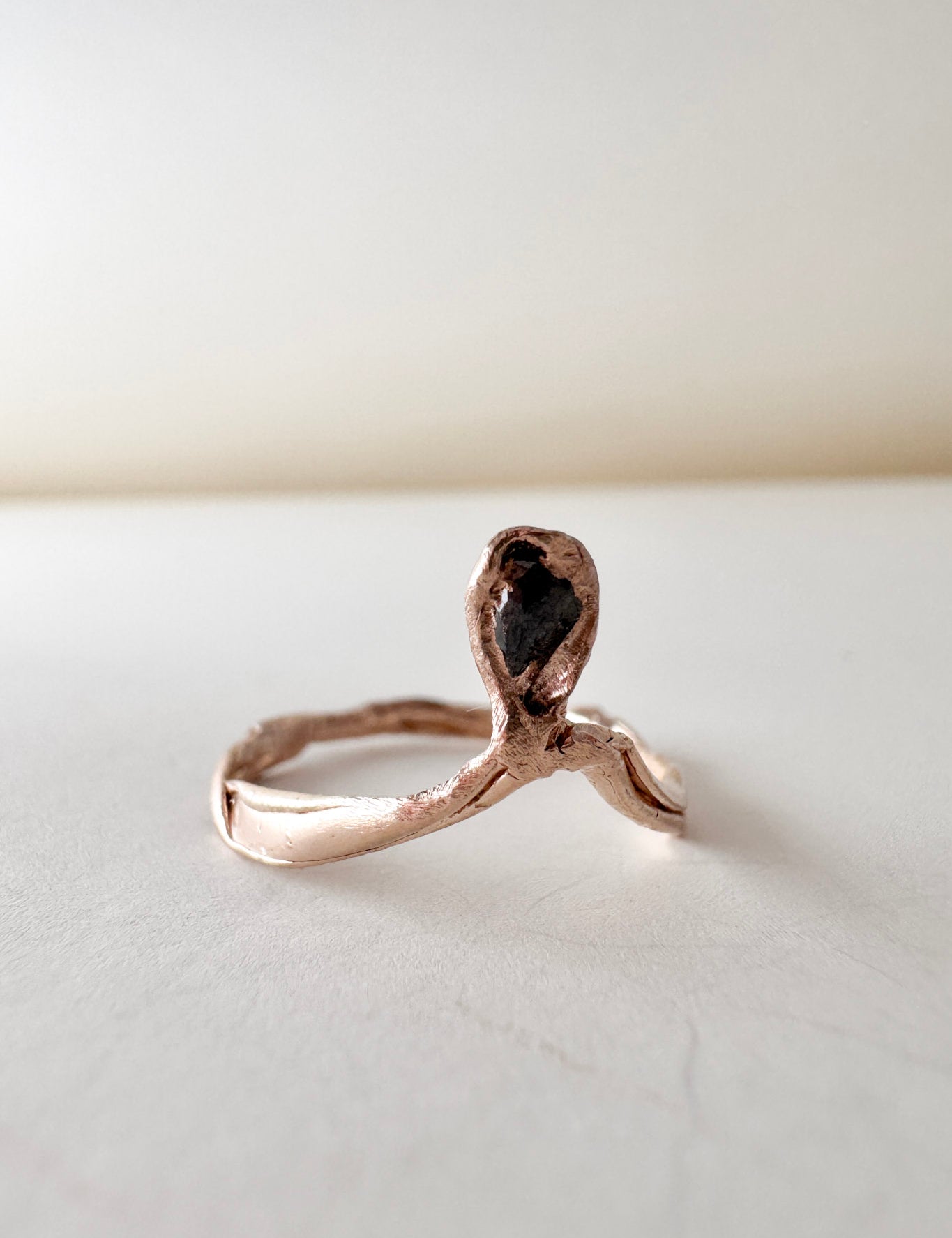 14k rose gold ring with a salt-and-pepper diamond in an organic sculpted band, shown front-facing on a white surface.