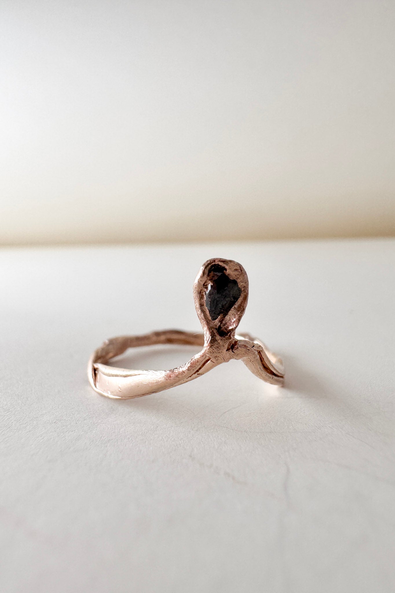 14k rose gold ring with a salt-and-pepper diamond in an organic sculpted band, shown front-facing on a white surface.