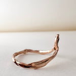 Side view of the 14k rose gold ring featuring a salt-and-pepper diamond, highlighting the asymmetrical sculpted band.