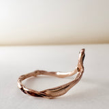 Side view of the 14k rose gold ring featuring a salt-and-pepper diamond, highlighting the asymmetrical sculpted band.