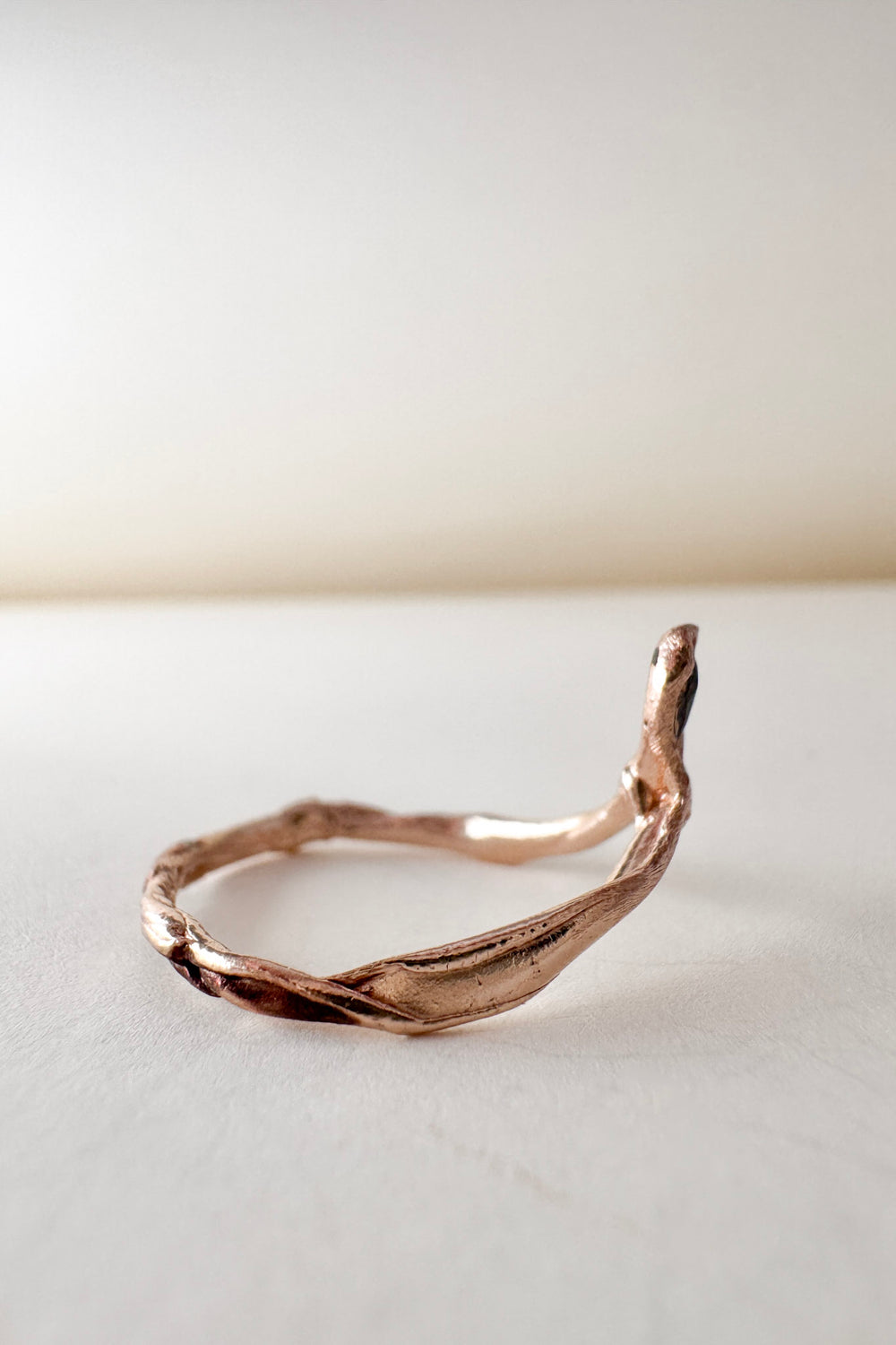 Side view of the 14k rose gold ring featuring a salt-and-pepper diamond, highlighting the asymmetrical sculpted band.
