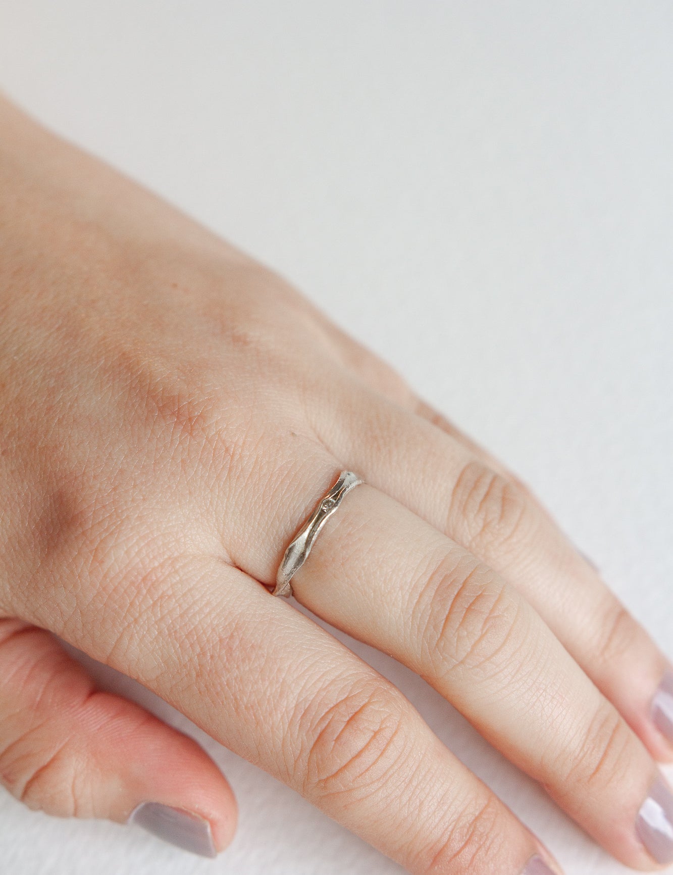 Nest Ring in sterling silver with a lab-grown diamond worn on a hand, photographed over a soft neutral surface.