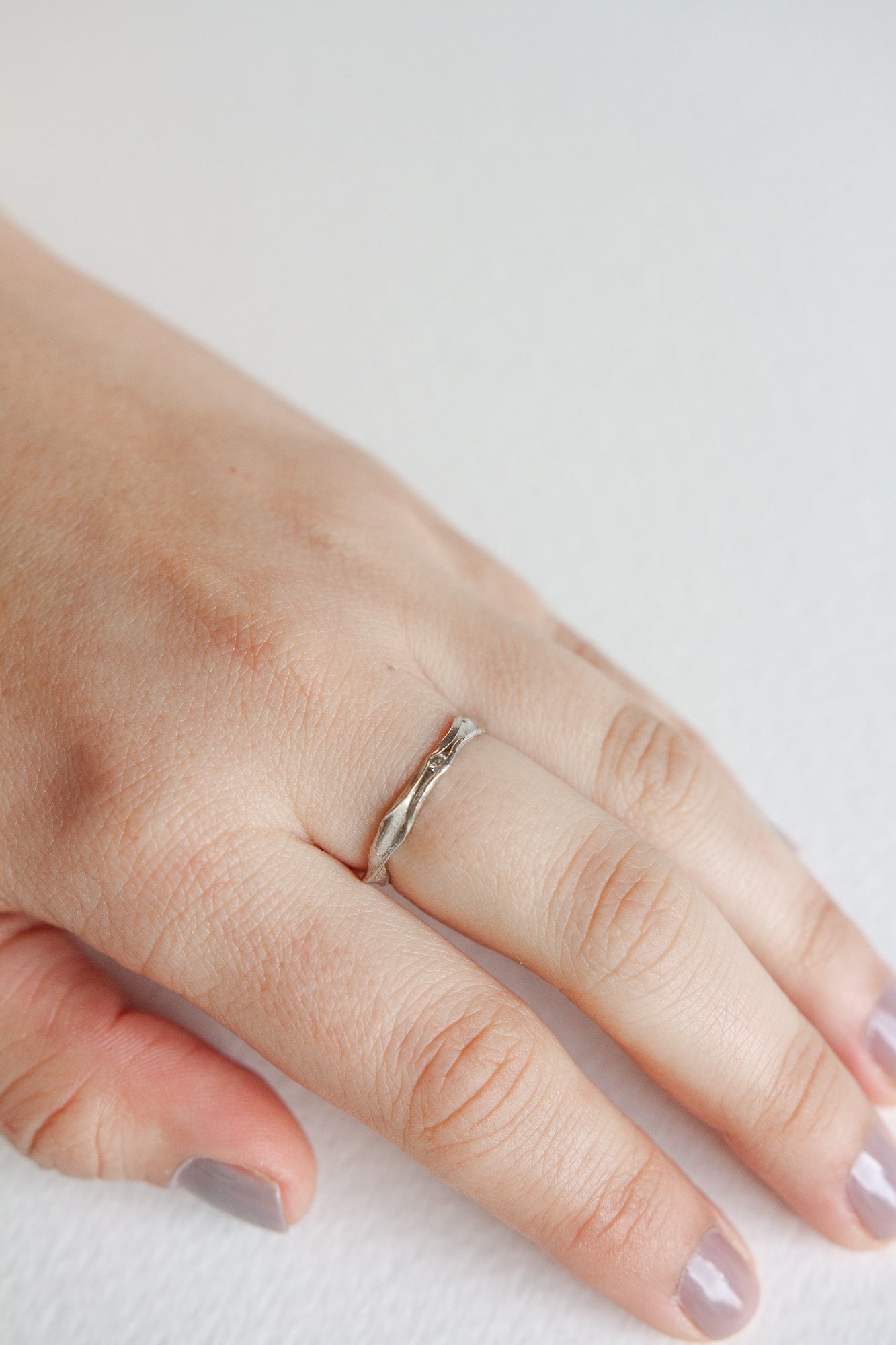 Nest Ring in sterling silver with a lab-grown diamond worn on a hand, photographed over a soft neutral surface.