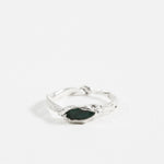 Front view of the sterling silver Refuge Ring showcasing a raw emerald embedded in an organic band, on a white background.