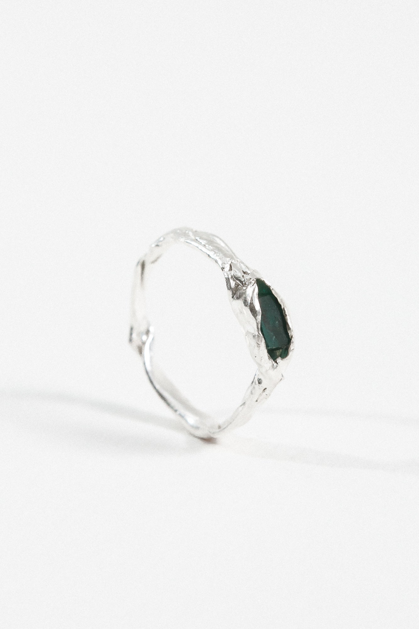 Side profile of the sterling silver Refuge Ring showing the organic handmade band and raw emerald.