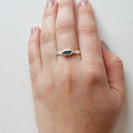 Refuge Ring with raw emerald in sterling silver worn on a hand, seen from a different angle, against a white backdrop.