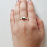 Refuge Ring with raw emerald in sterling silver worn on a hand, seen from a different angle, against a white backdrop.