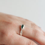 Sterling silver Refuge Ring with a raw emerald worn on a hand, photographed against a light neutral background.