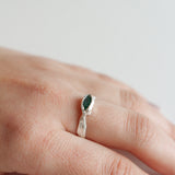Sterling silver Refuge Ring with a raw emerald worn on a hand, photographed against a light neutral background.