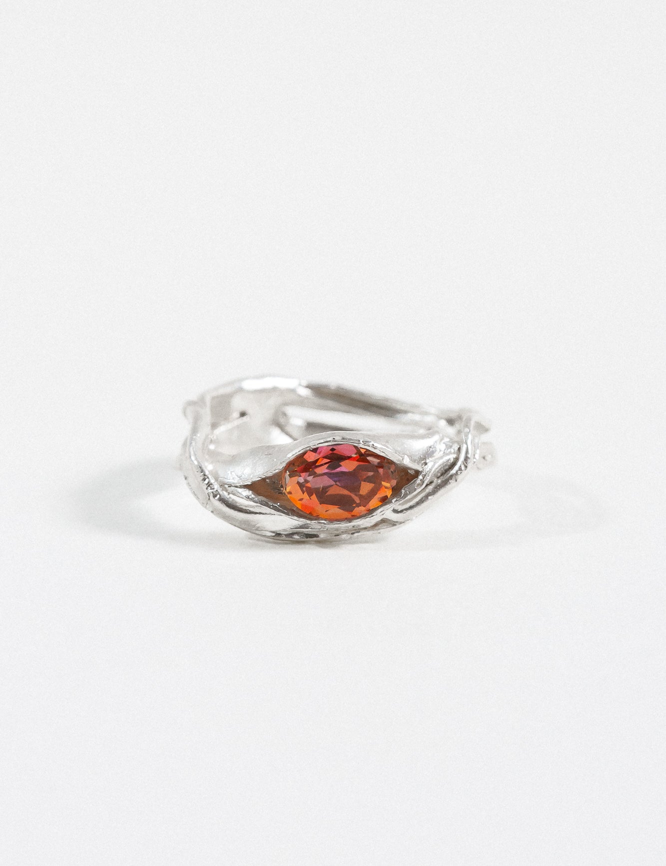 Silver ring with an organic band design and a central orange gemstone, photographed on a white background.